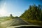 Glare on the car front window and view on nature landscape with road and trees