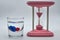 Glass of alcohol containing red and blue dice with gorgeous vintage pink hourglass