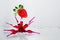 Glass ampoules with a red medicine vitamine b12 glued together in a spider shape on a glass laboratory shelf with a strawberry on