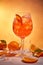 Glass of Aperol spritz cocktail on orange background