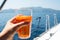 Glass of aperol spritz in the hand of a young woman, a boat trip