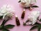 Glass aromatic oil bottles and peony flowers on pink pastel background