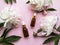 Glass aromatic oil bottles and peony flowers on pink pastel background