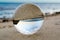 Glass ball lens lies on the sand of the sea shore