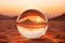 A glass ball in the middle of the desert in the rays of sunset. Close-up, beautiful view