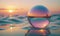 A glass ball is sitting in the water at sunset.