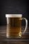 Glass of barley beer with foam on a dark wooden background, alcoholic beverage