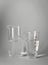 Glass beakers with water on light background