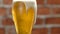 Glass of beer close-up with froth over brick wall