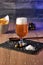 Glass of beer with foam and snacks in the background. Elaboration of craft beer. Brewing