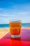 Glass of beer on red table at the shore of the beach
