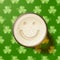 Glass of beer with smiley on clover background