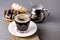 Glass of Black Americano Coffee and Tasty Chocolate and Vanilla Donuts on Wooden Tray Gray Background Morning Breakfast Lifestyle