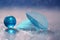 A glass blue ball and a transparent leaf skeleton on a glass table with reflection and a beautiful bokeh.