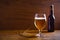 Glass and bottle of beer, ears of barley on wooden background. Ale