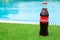 Glass bottle of coca cola stands on green grass of lawn