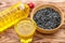 Glass and bottle of cooking oil with bowl of sunflower seeds on wooden table