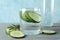 Glass and bottle with cucumber water and slices on table, close up