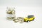 A glass bottle filled with coins labelled car with a small yellow toy ca