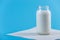 Glass bottle with fresh milk on blue background. Colorful minimalism. Healthy dairy products with calcium