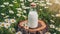 Glass bottle of fresh milk on tree stump, green grass and daisies. Tasty and healthy beverage