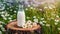 Glass bottle of fresh milk on tree stump, green grass and daisies. Tasty and healthy beverage