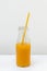 Glass bottle with juice and pasta straw on light background, vertical image