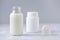 Glass bottle of milk and powder on gray background