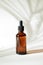 Glass bottle with moisturizing serum. Brown bottle with a dropper on a background of tropical shadow of a palm leaf. The concept