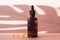 Glass bottle with moisturizing serum on a pink background with vitamin c capsules. Brown bottle with a dropper on a background of