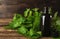 Glass bottle of nettle oil with leaves on wooden table, closeup. Space for text