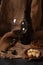 Glass and bottle of red wine with cheese, raisins, and nuts on sackcloth, dark background