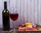 Glass and bottle of red wine, cheese, salami, walnuts, prosciutto and rosemary on wooden background