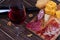 Glass and bottle of red wine, cheese, salami, walnuts, prosciutto and rosemary on wooden background