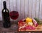 Glass and bottle of red wine, cheese, salami, walnuts, prosciutto and rosemary on wooden background