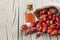Glass bottle of rosehip seed essential oil with fresh rose hip fruits on wooden rustic background