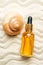 Glass bottle with serum cosmetic product on the background of seashells and sea beach sand. product presentation on a sandy