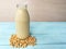 A glass bottle soy milk, soybeans seed around base, blue wooden table,