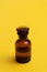 Glass bottle on yellow background. Perfume, medicine, chemistry background.