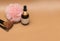 Glass bottles for cosmetics, natural, essential oils isolated on a brown background with pink pompom make-up brushes