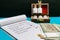 Glass Bottles of homeopathy pills in old open wooden box with Indian currency and notepad on blue and dark background