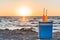 glass bottles with summer drinks and straws on cooler at sandy