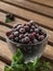 Glass bowl with blackcurrant berries in a frost on a dark wooden table. Nearby are mint leaves and blackcurrant berries,