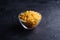 Glass bowl with cavatappi uncooked golden wheat curly pasta on textured dark black background