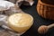 A glass bowl with cream-colored honey on a dark table near the honey Mace and basket