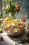 A glass bowl filled with a salad next to a vase of flowers. Spanish dish, ensaladilla rusa.