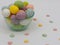 Glass bowl filled with string decorated Easter eggs with little candies on white background, perfect decor for the holiday,