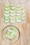 Glass bowl full of granny smith apple slices on a butcher block table, and slices laid out on a mesh tray ready for dehydrating ap