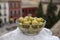 Glass bowl with green andalusian olives served on outdoor terrace with view on old part of Granada, Andalusia, Spain