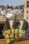 Glass bowl with green andalusian olives served on outdoor terrace with view on old part of Granada, Andalusia, Spain